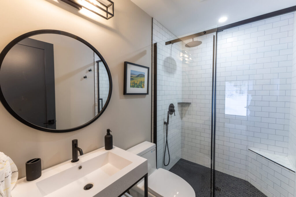 A glass shower with white tiles next to a white vanity