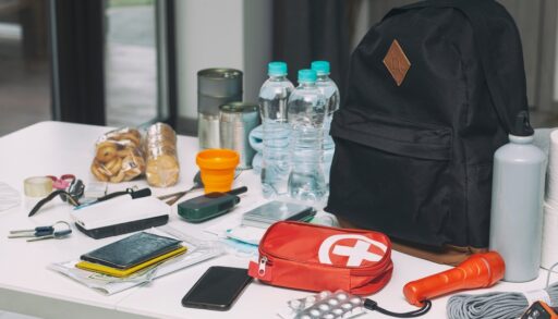 Emergency kit organized on the table. Documents, water, food, first aid kit and another items needed to survive.