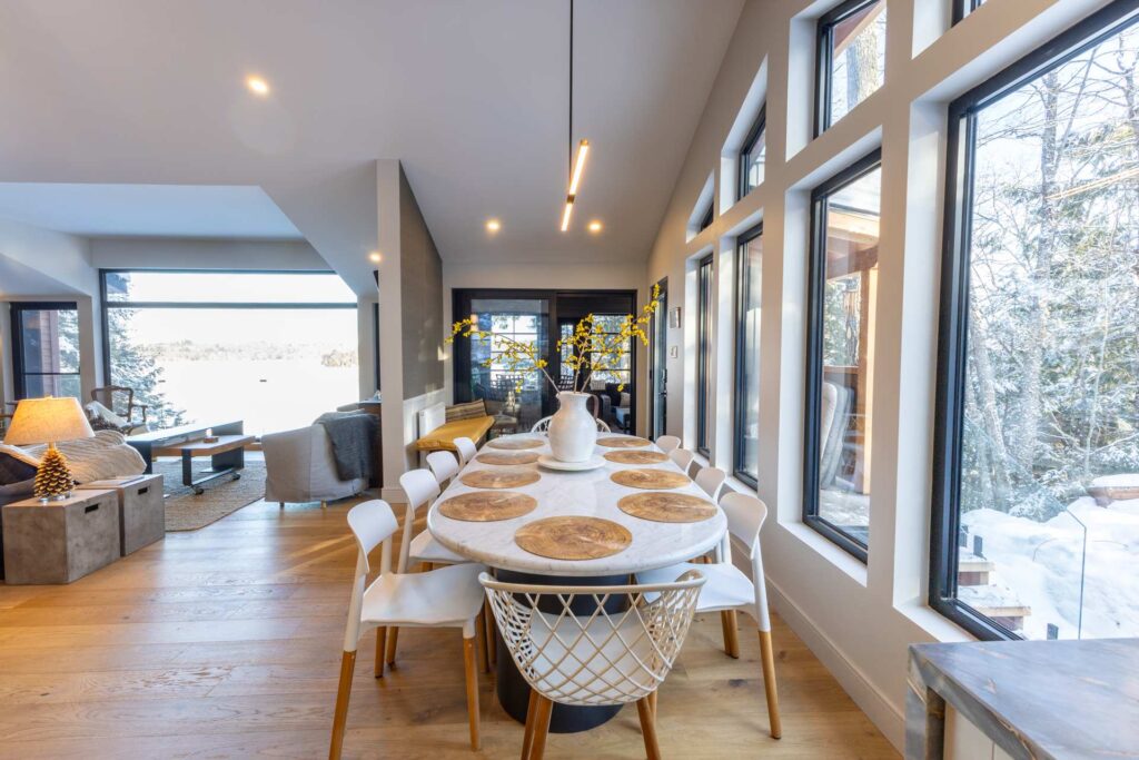A long white dining table next to windows