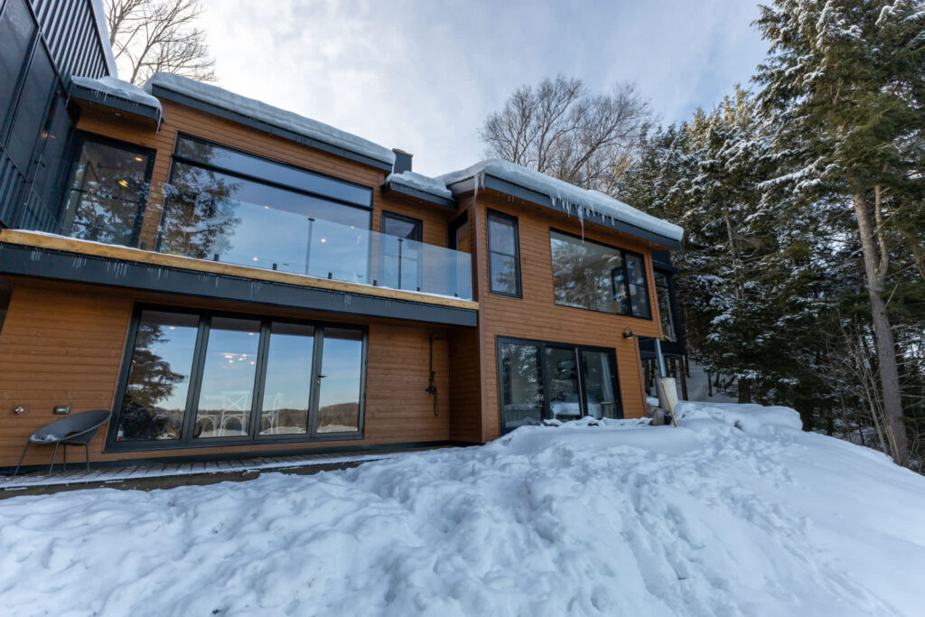 A large two-story brown paneled cottage in the snow