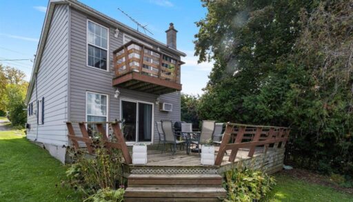 A grey two-story cottage with an upper-level wood deck and a lower-level wood deck