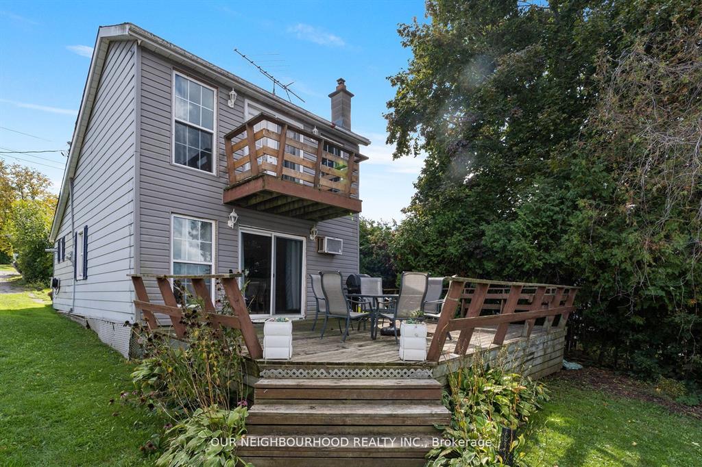 A grey two-story cottage with an upper-level wood deck and a lower-level wood deck