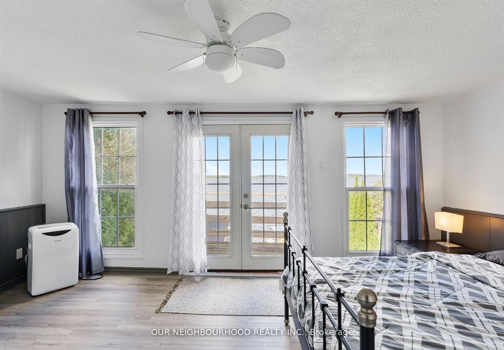 A bed sits next to bright floor-to-ceiling windows with French doors