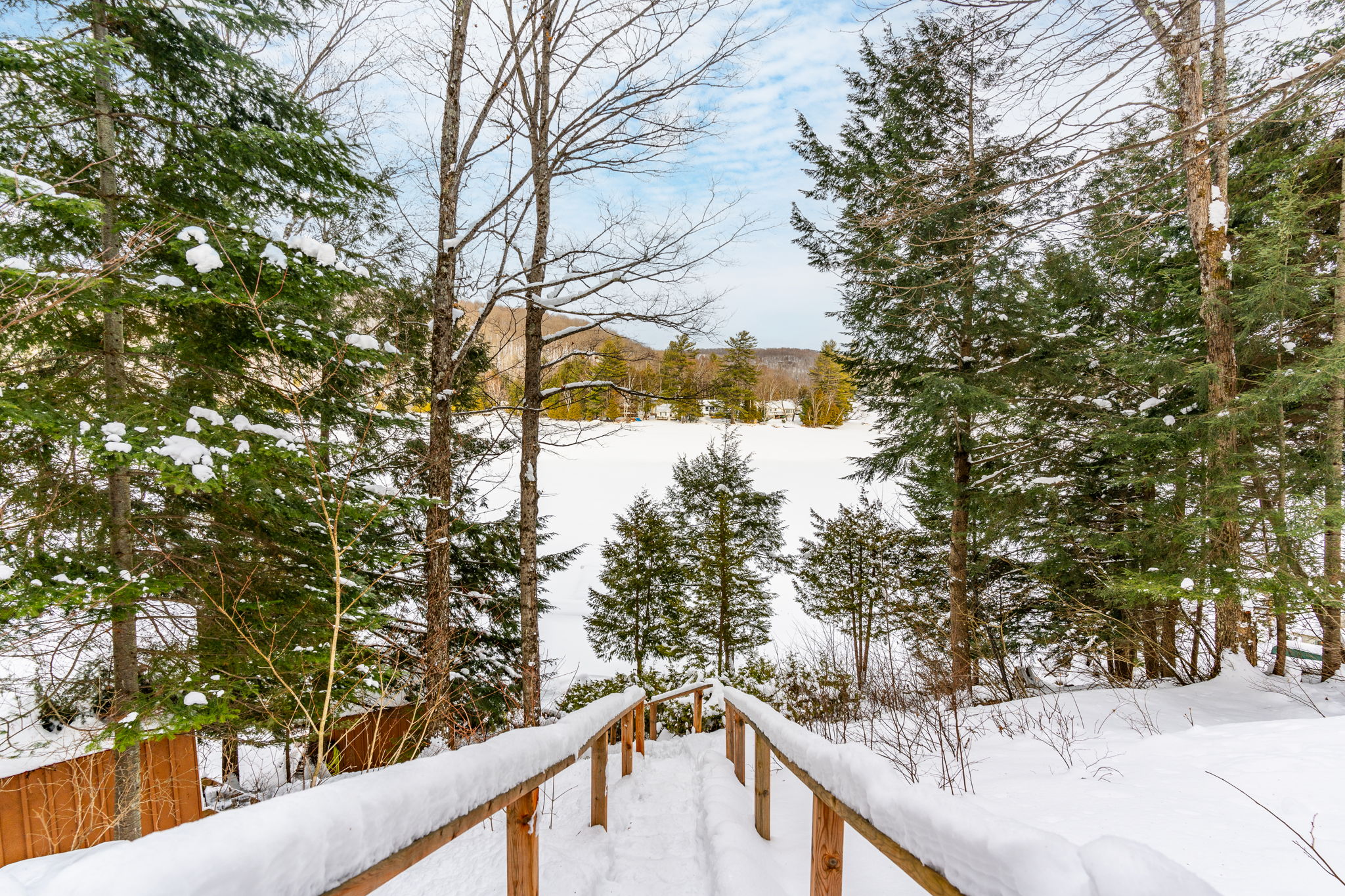 Wood steps covered in snow lead down to a snow-covered lake