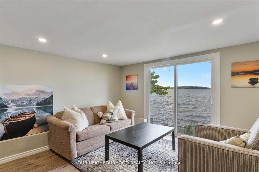 A small beige couch faces a black coffee table next to floor-to-ceiling lakefront windows