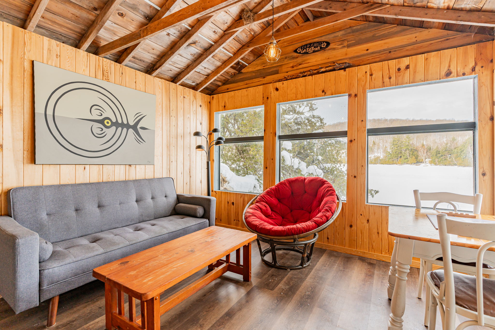 A wood bunkie with large windows. A grey couch