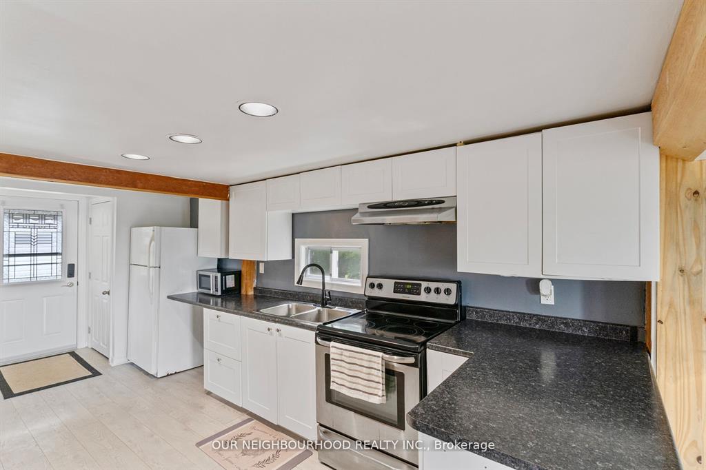 A white kitchen with a black countertops and a stainless steel stove
