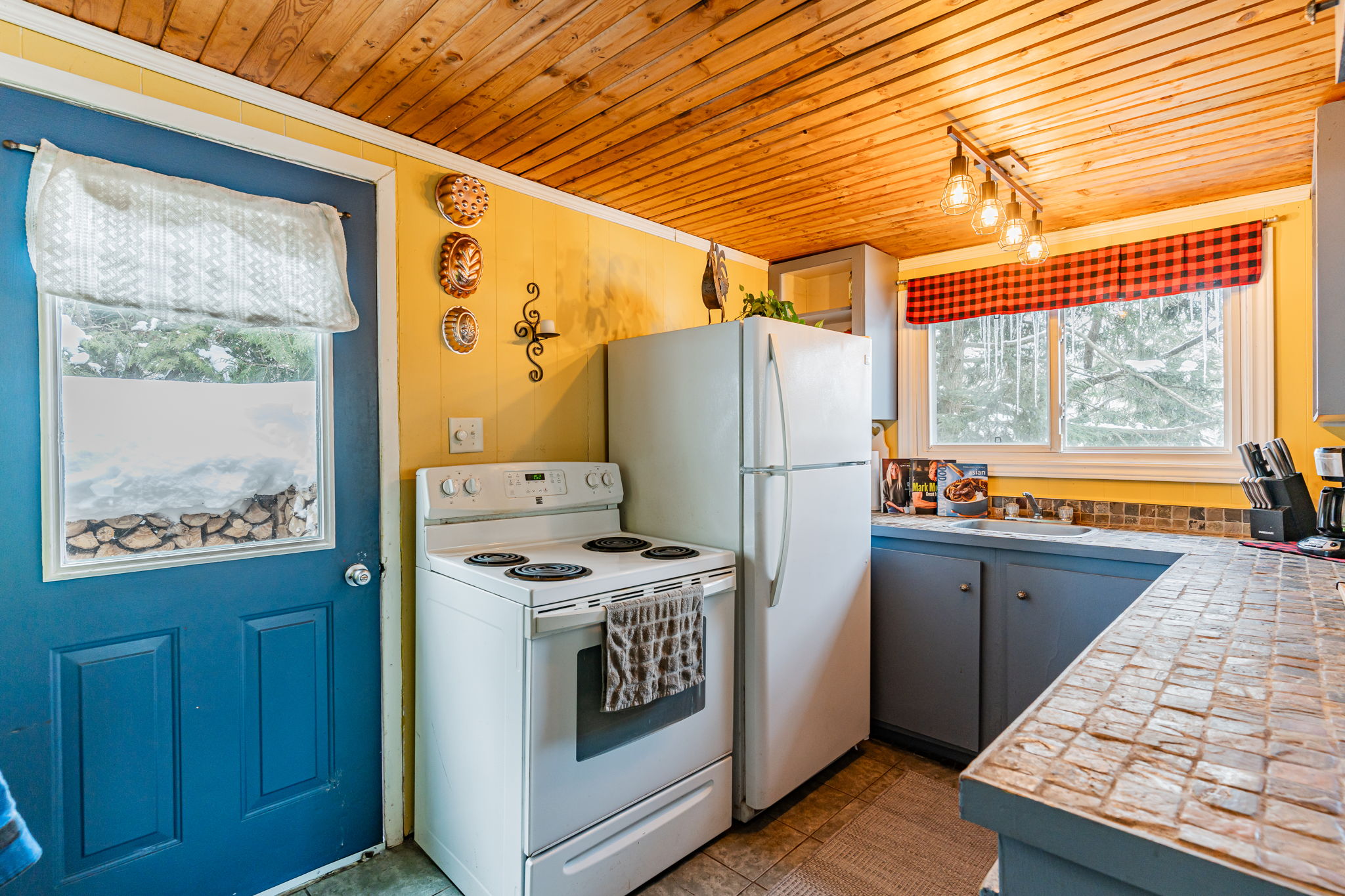 Inside a wood cabin, white appliances face a blue countertop