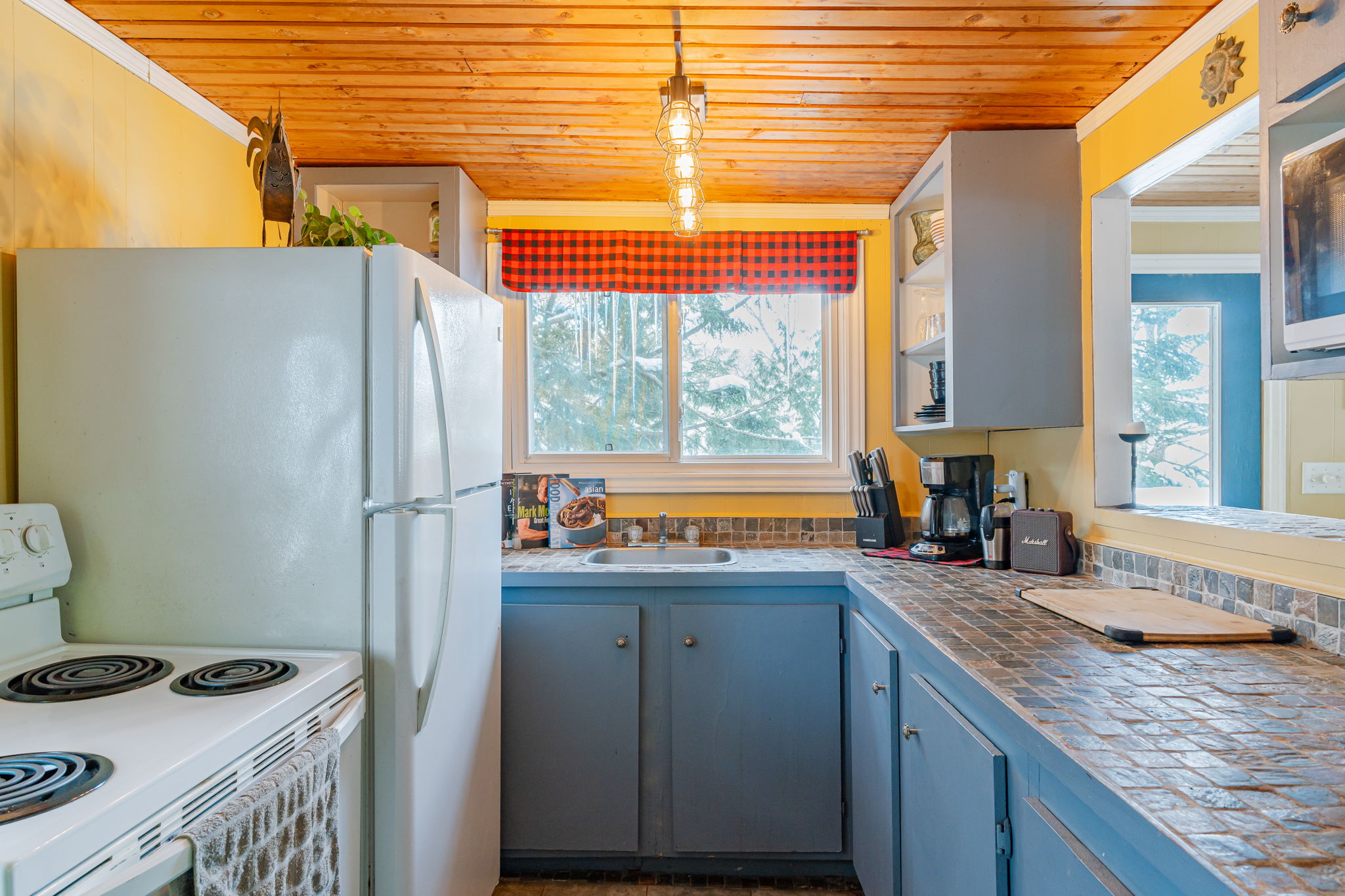 A small kitchen with blue lower-level cabinets and white appliances
