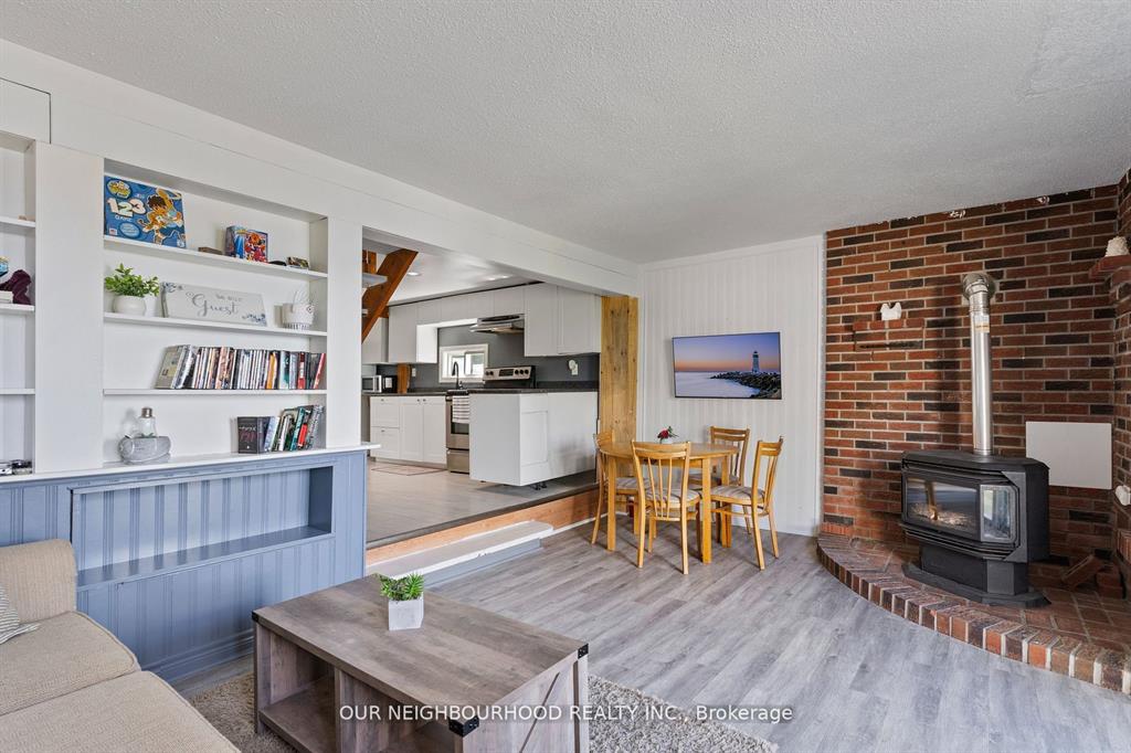 In a spacious living room, a built-in blue and white bookshelf faces a grey coffee table. Across the room, a small round wood dining table.