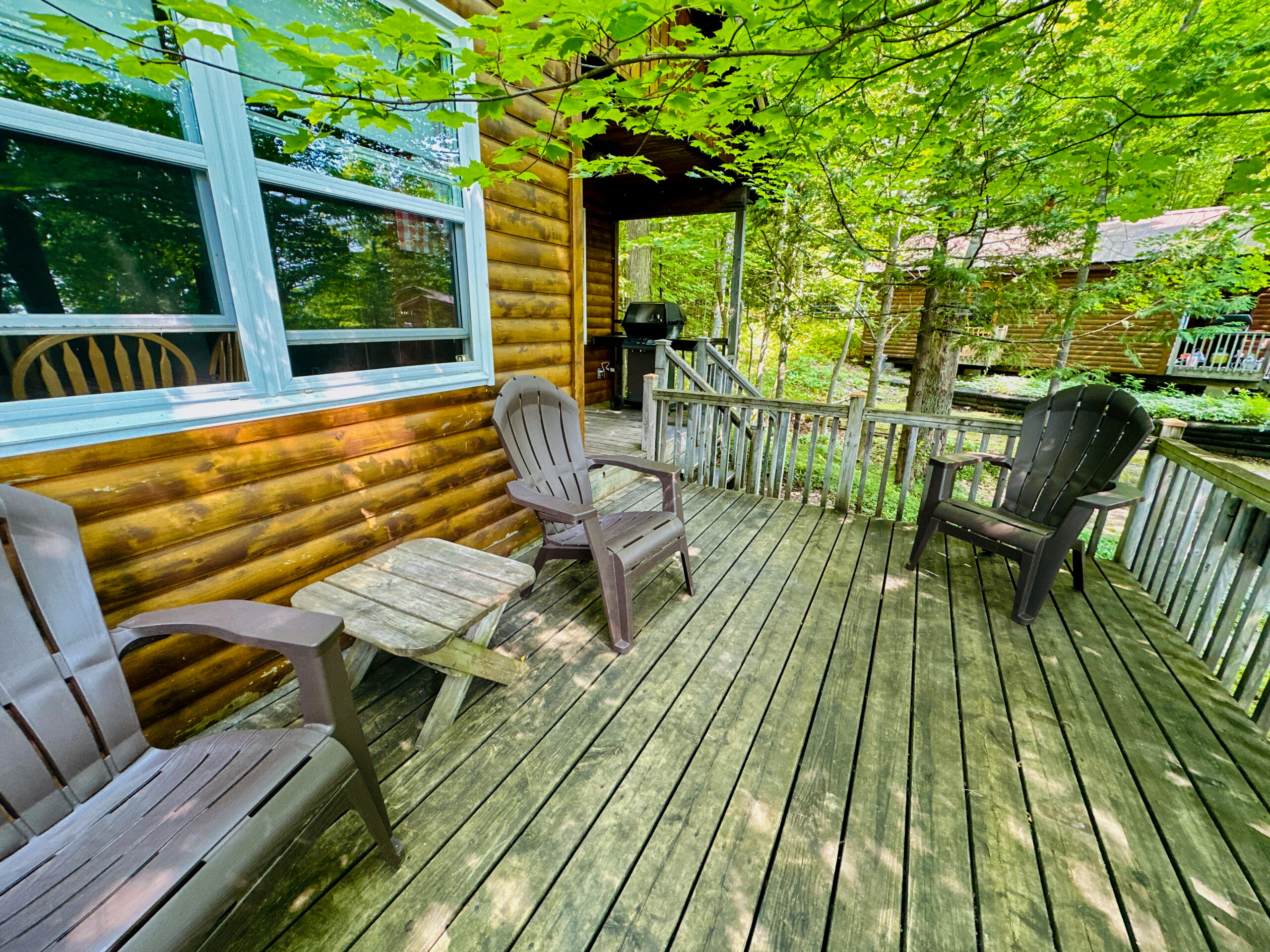 A large wooden deck attached to a cabin, complete with seating and overlooking the natural surroundings.