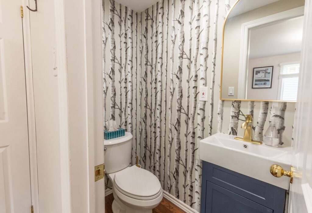 A narrow bathroom with birch-lined wallpaper
