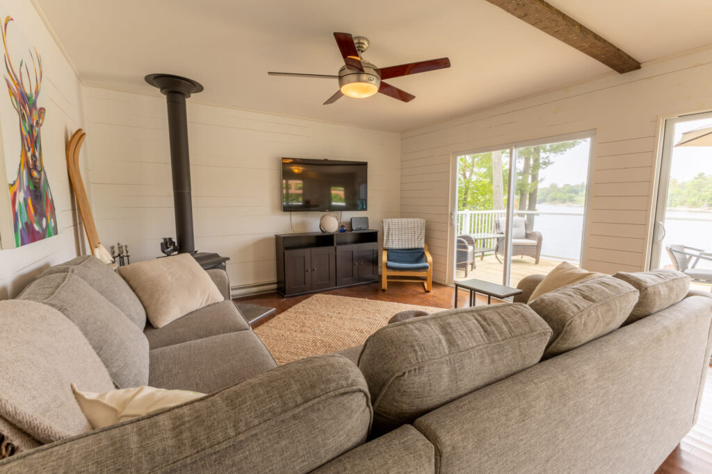 A grey couch faces a flat-screen TV and a wood stove