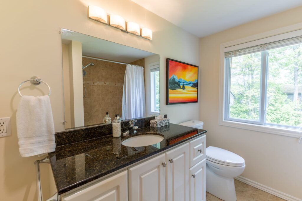 A bright bathroom with black marble countertops and white cabinets