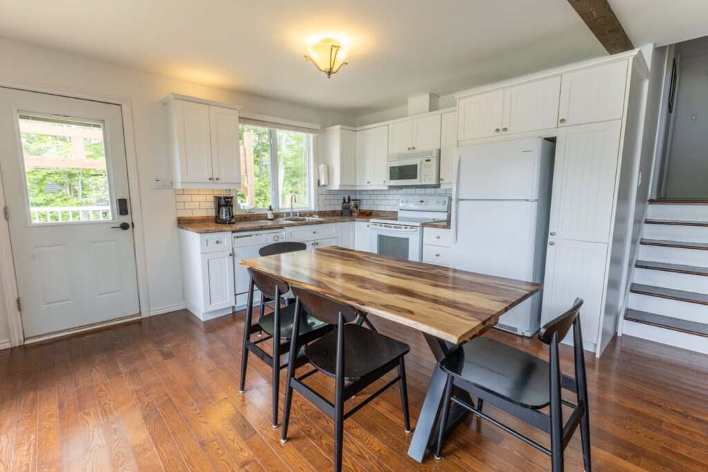 A long wood table in an open-concept white kitchen