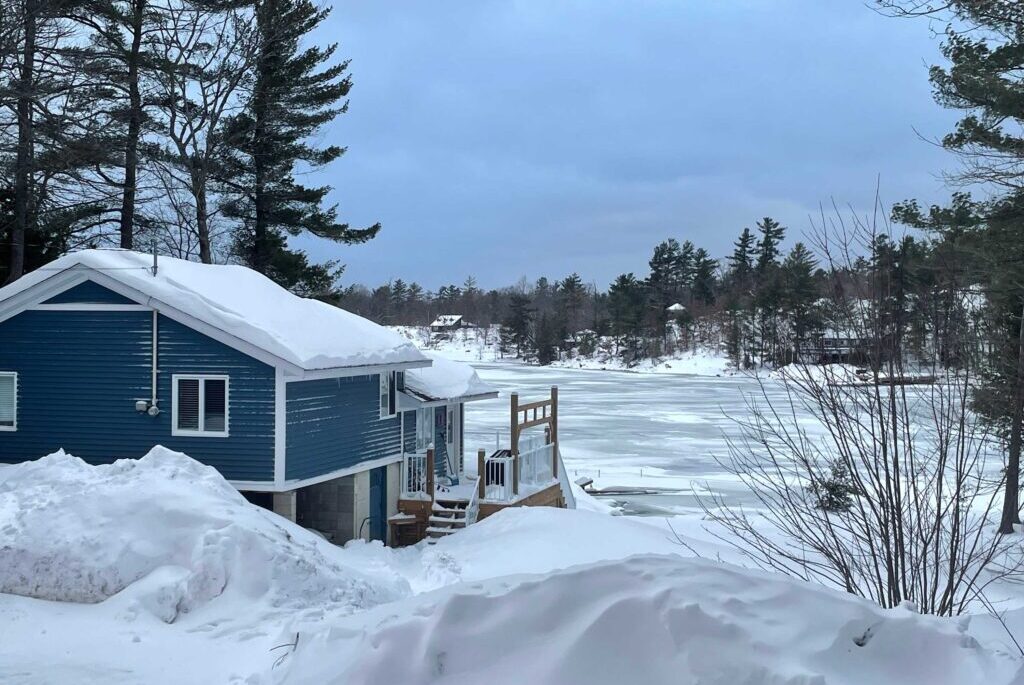 A snowy side entrance to a blue cottage