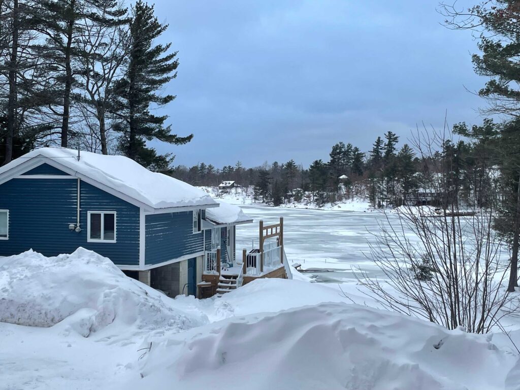 A snowy side entrance to a blue cottage