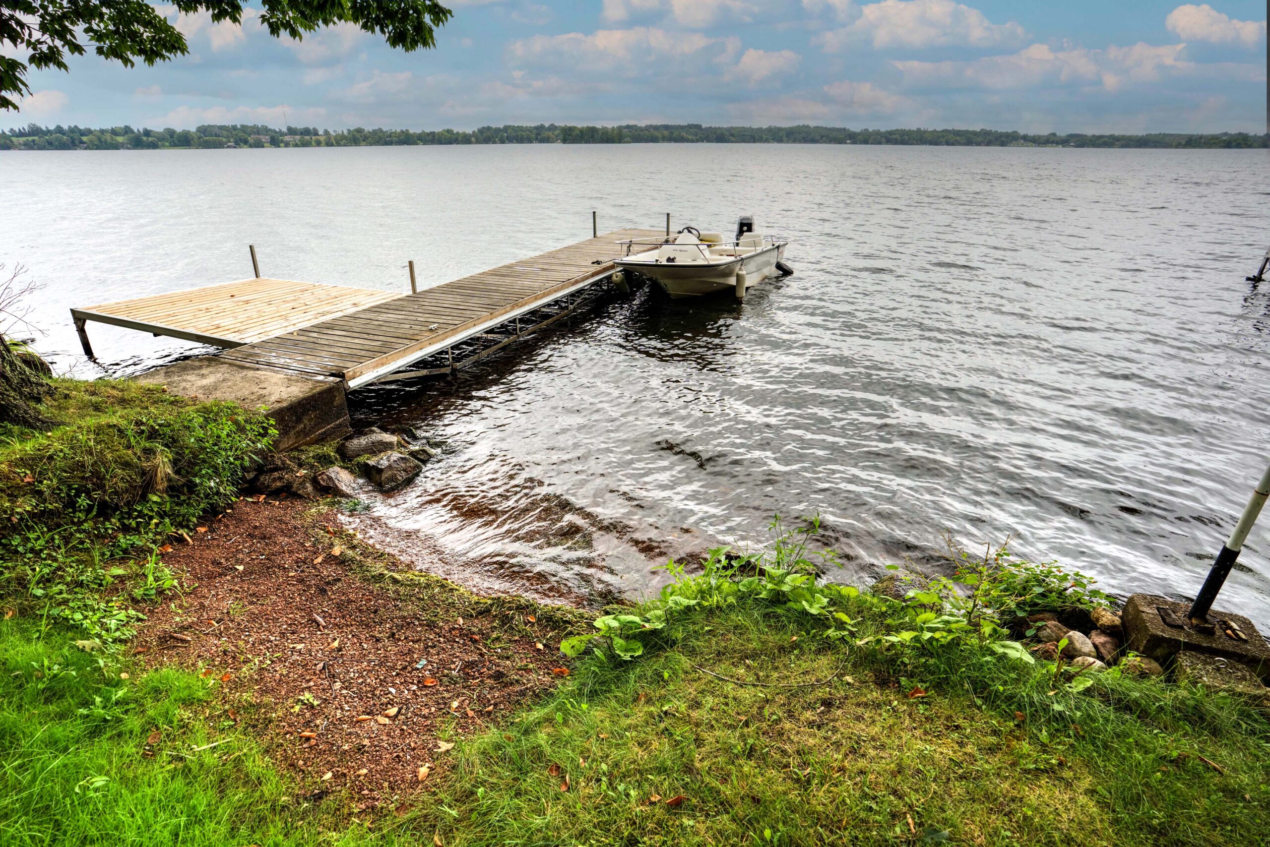 A dock sits in the lake next to a grassy shoreline