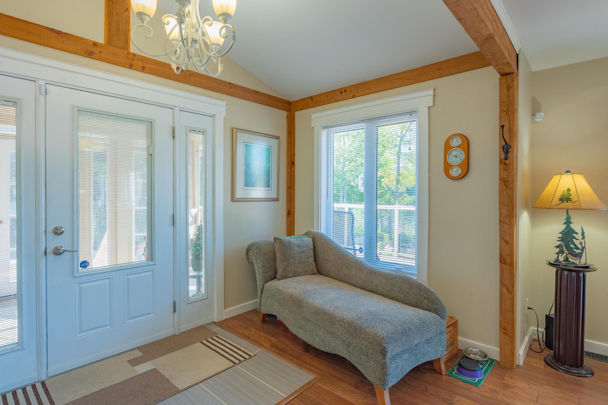 A cozy living room featuring vaulted ceilings, wooden beams, and comfortable seating.