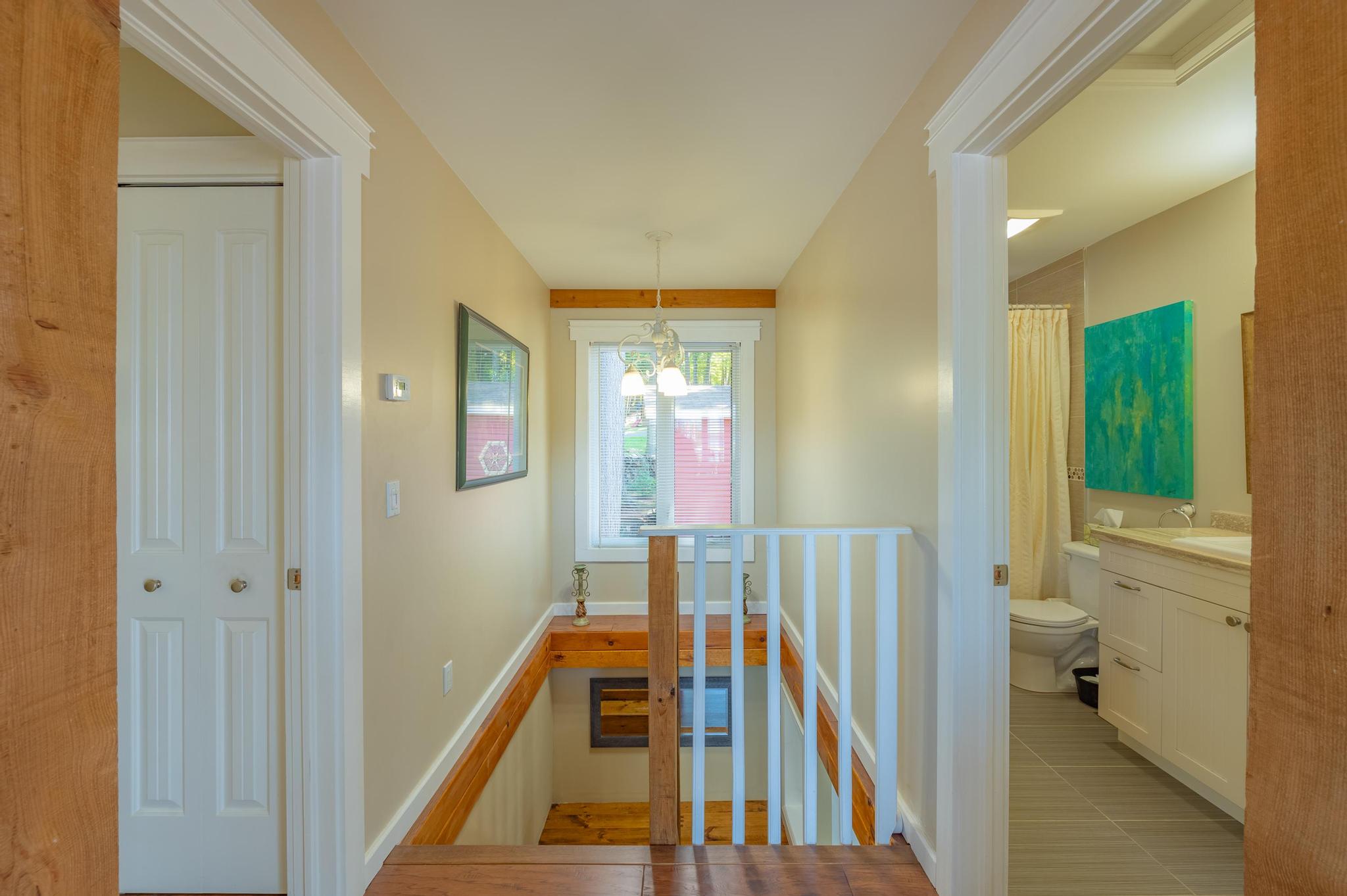 A wooden staircase leading to the upper level of the cottage, featuring a modern railing.