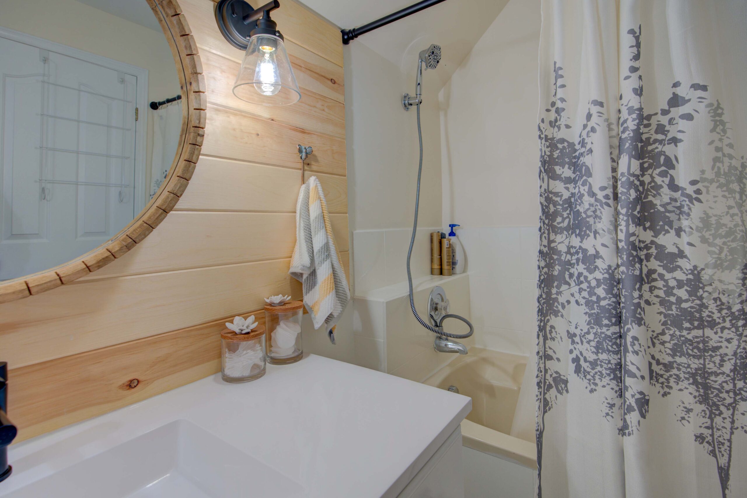 A white bath tub with an open shower curtain is beside the white bathroom vanity