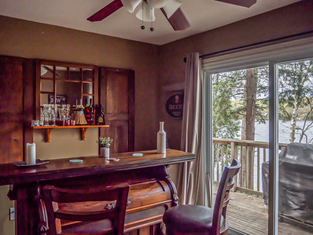A wood dining table with wood chairs facing a sliding glass door