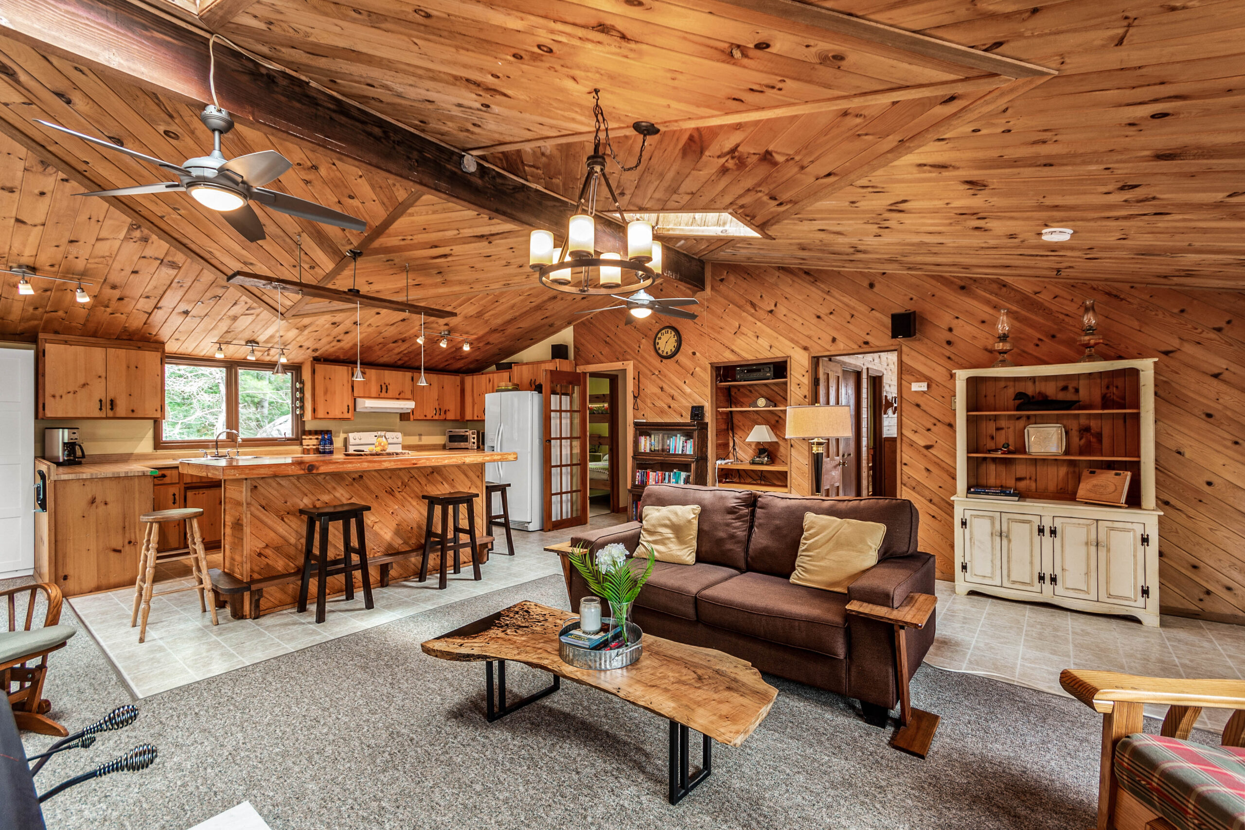 A wood-paneled room with high ceilings and a brown couch with a wood table