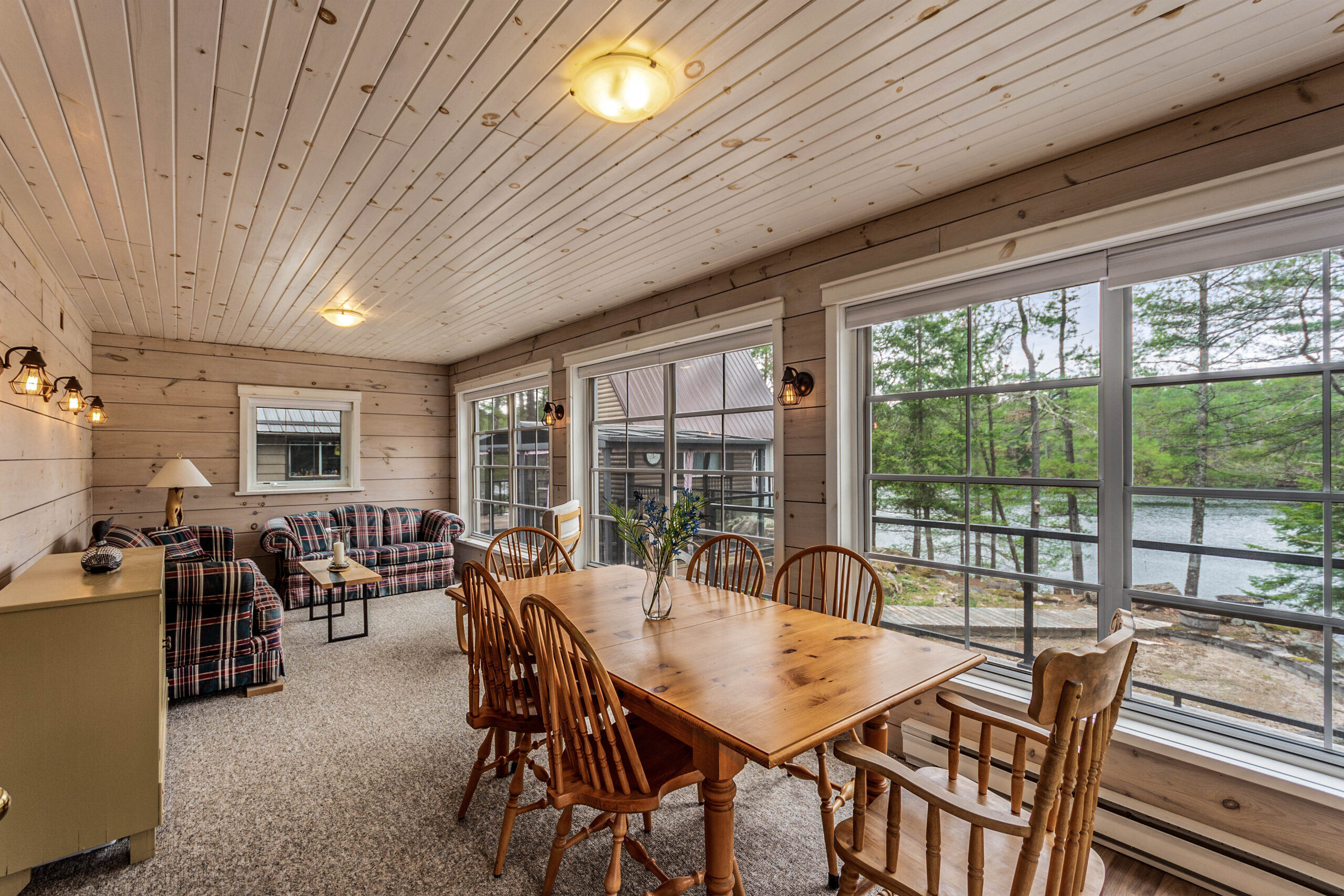 A wood dining table with wood chairs in a bright sunroom