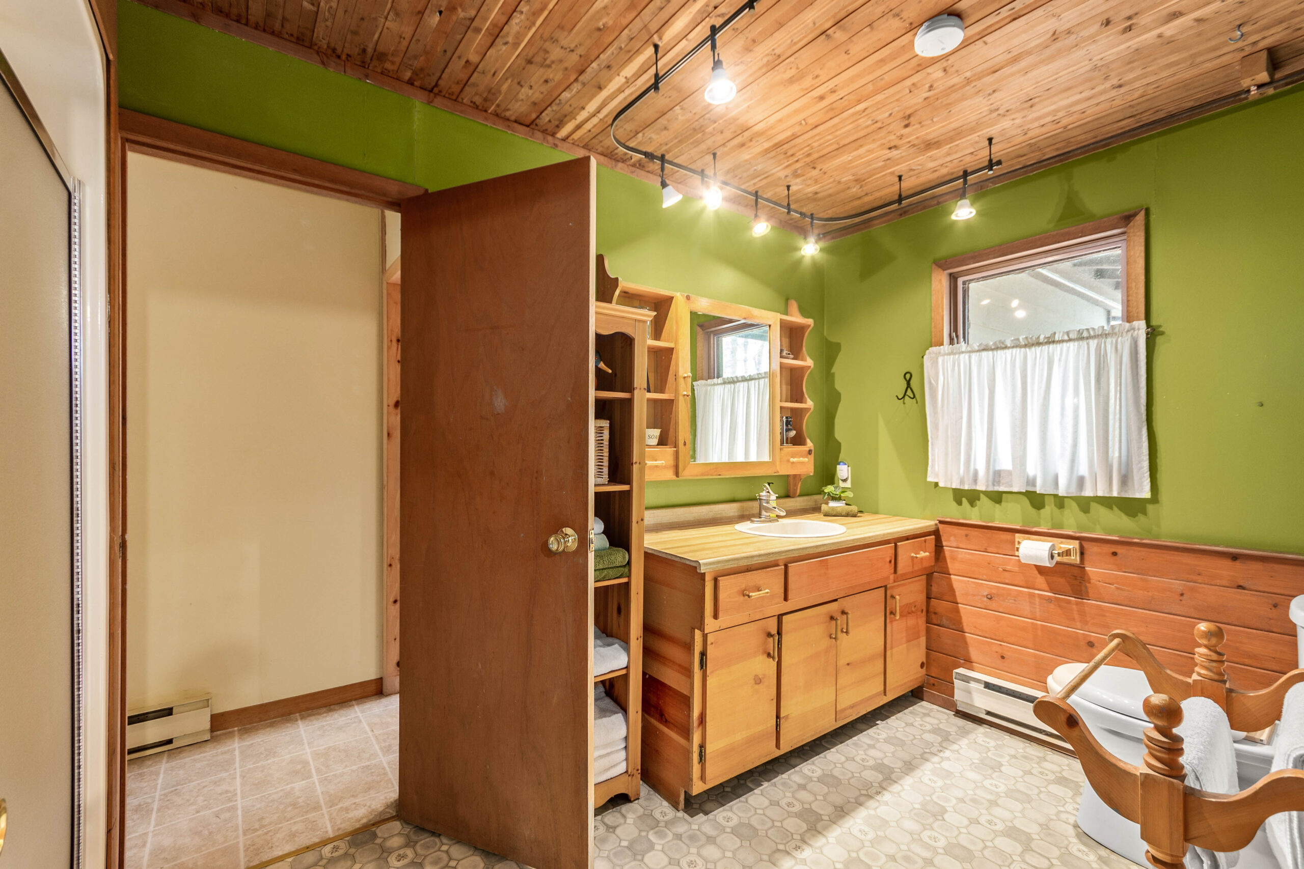 A lime green bathroom with wood cabinets