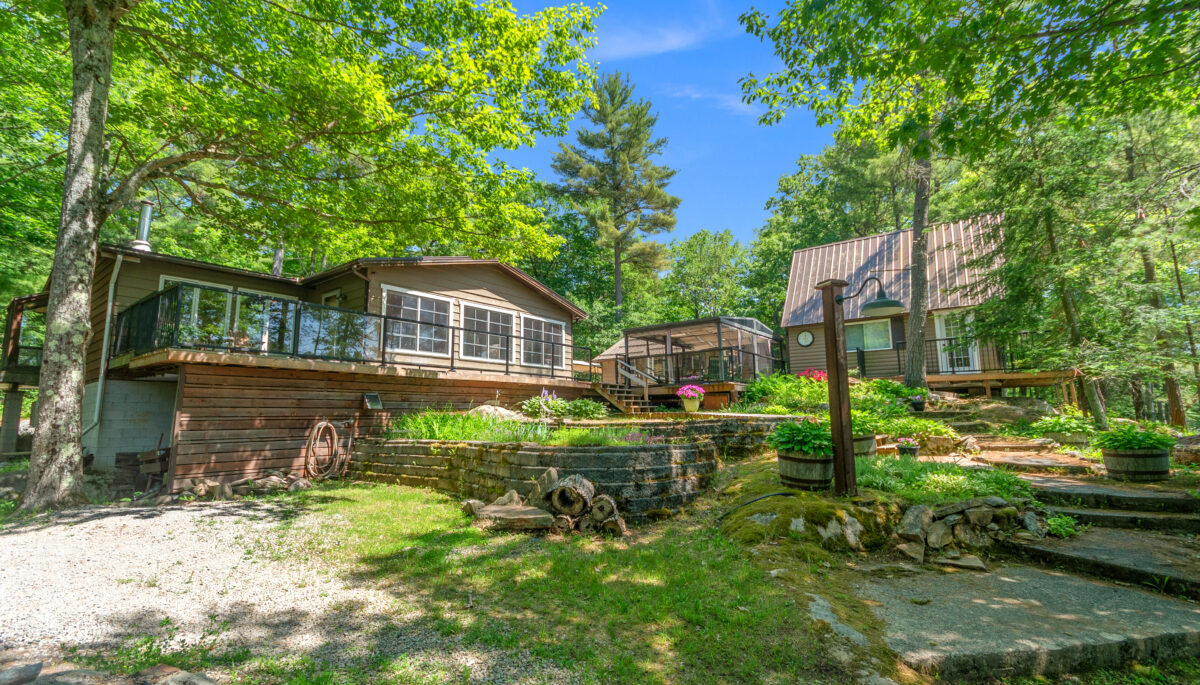 A wood cottage with a large deck in a grassy forest