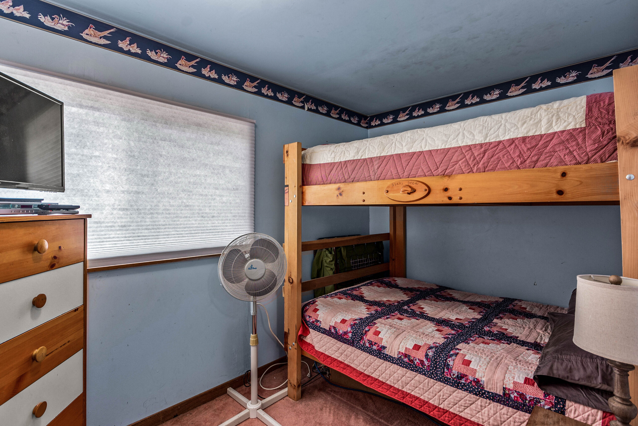 Wood bunk beds with red bedspreads in a blue room