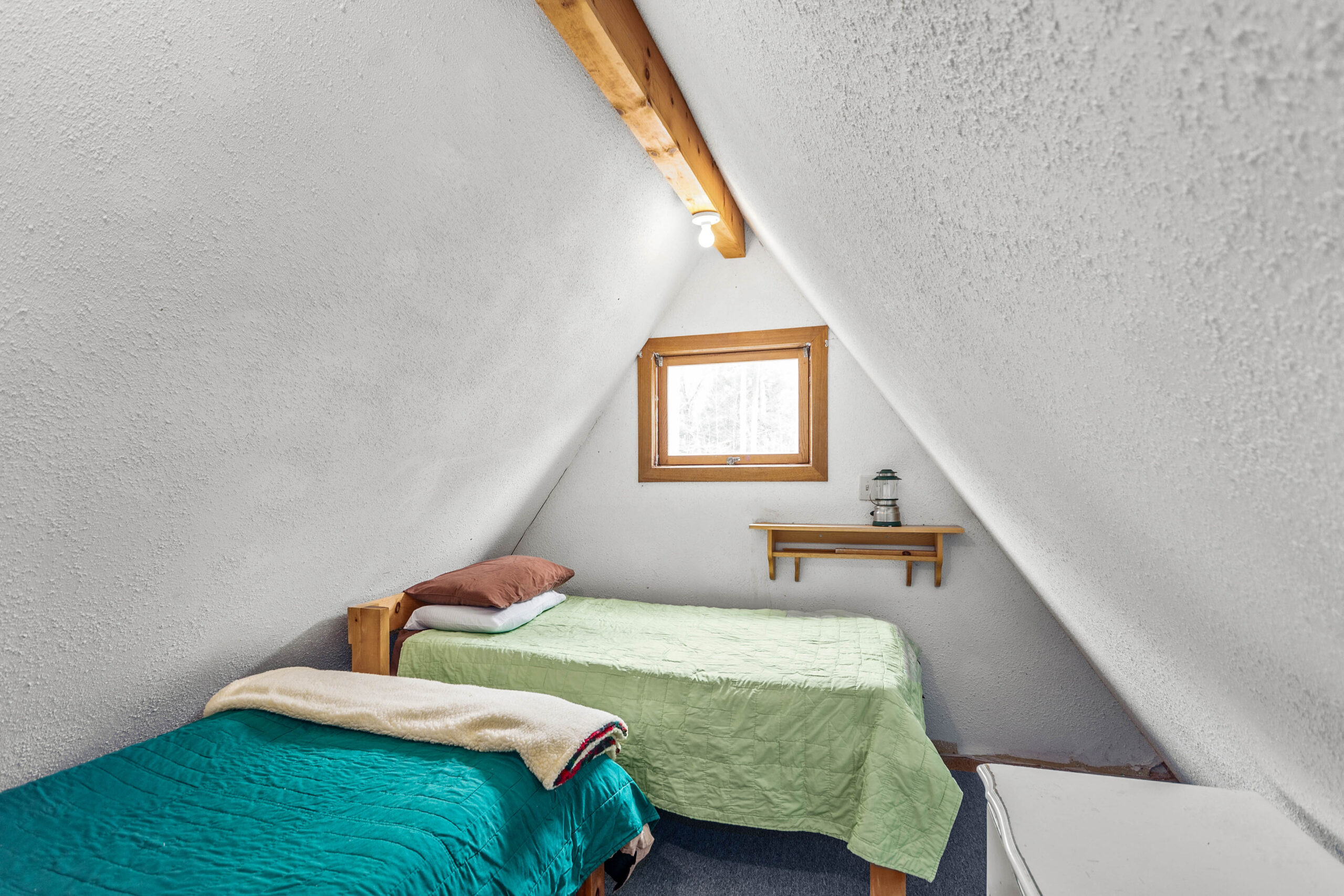 a white loft area with a teal bed and a green bed