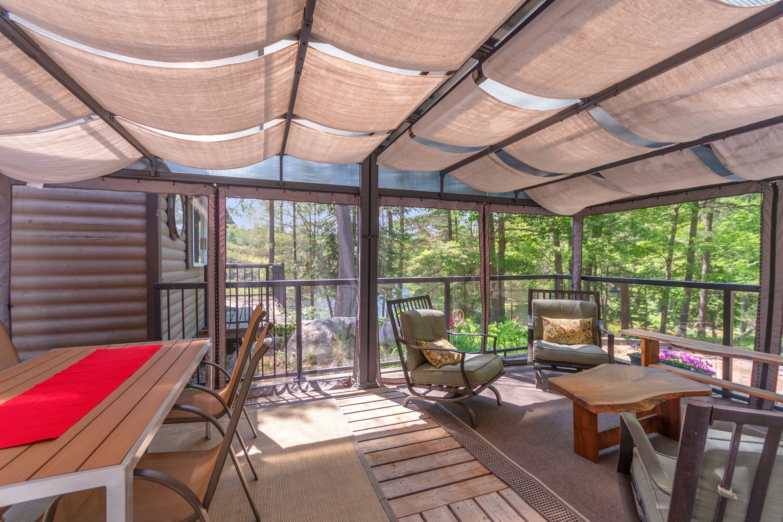 A screened-in porch with a dining table and a small sitting area