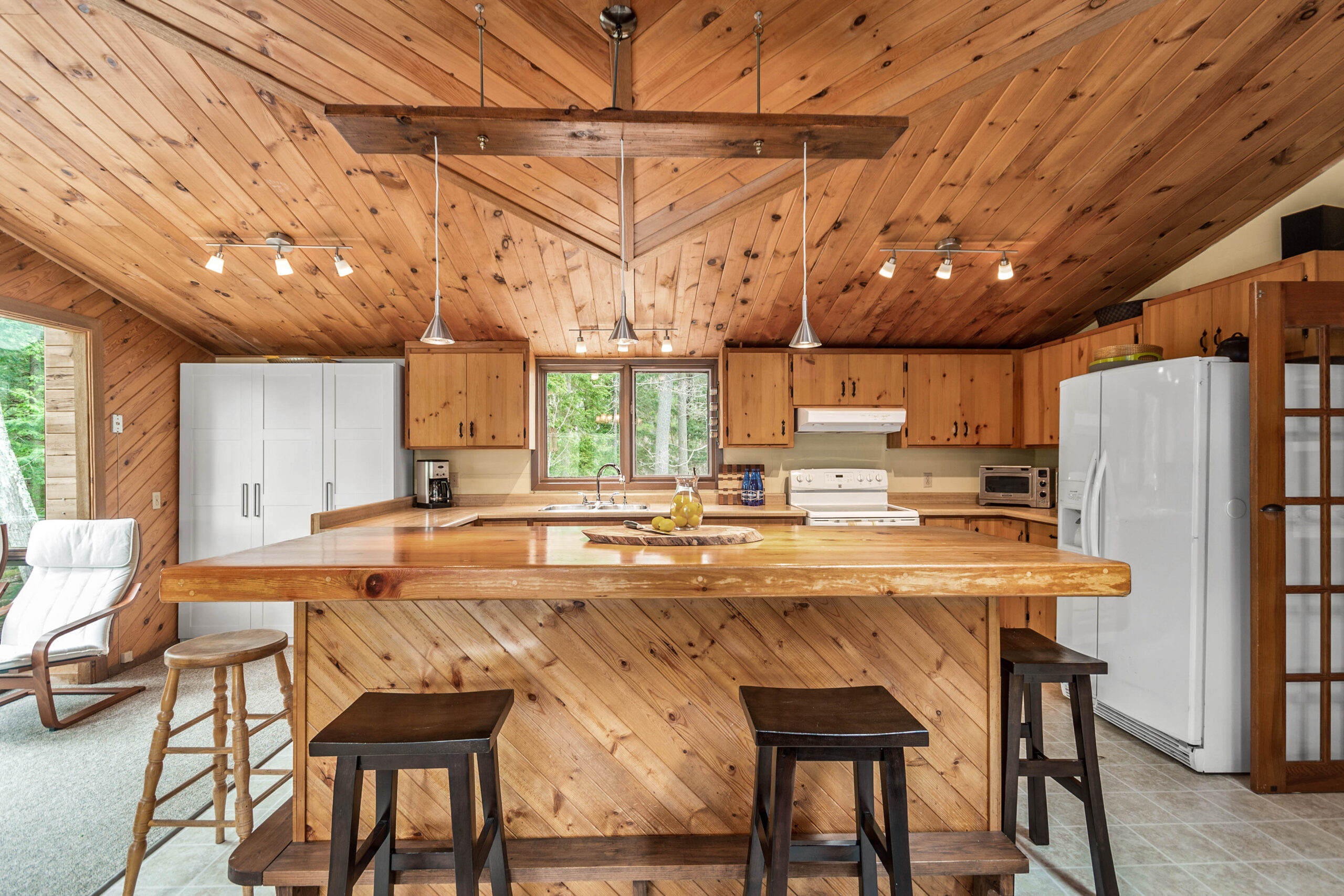 A wood kitchen island with dark brown stools in a wood-paneled kitchen