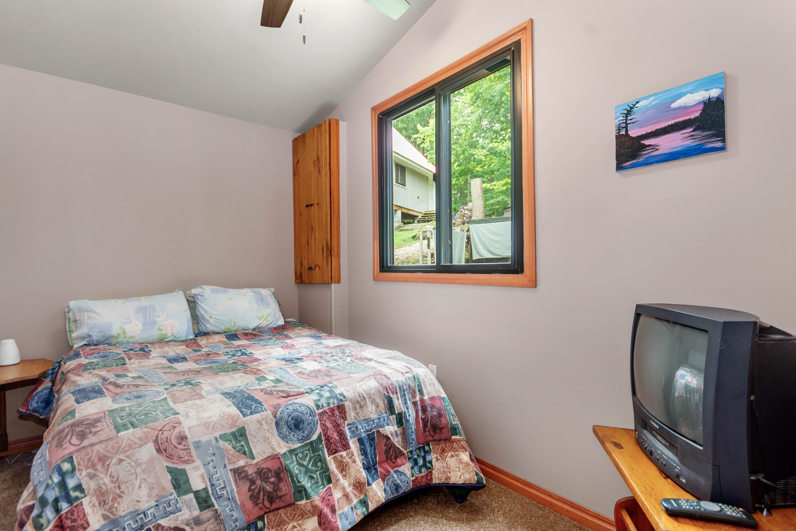 A patterned bed in a white room with a window to the right