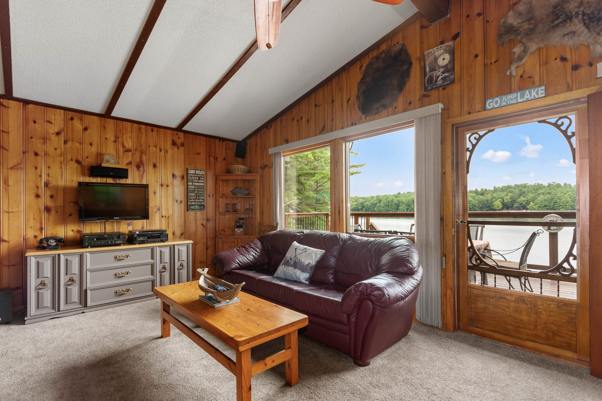 A burgundy leather couch faces away from a lake-facing window