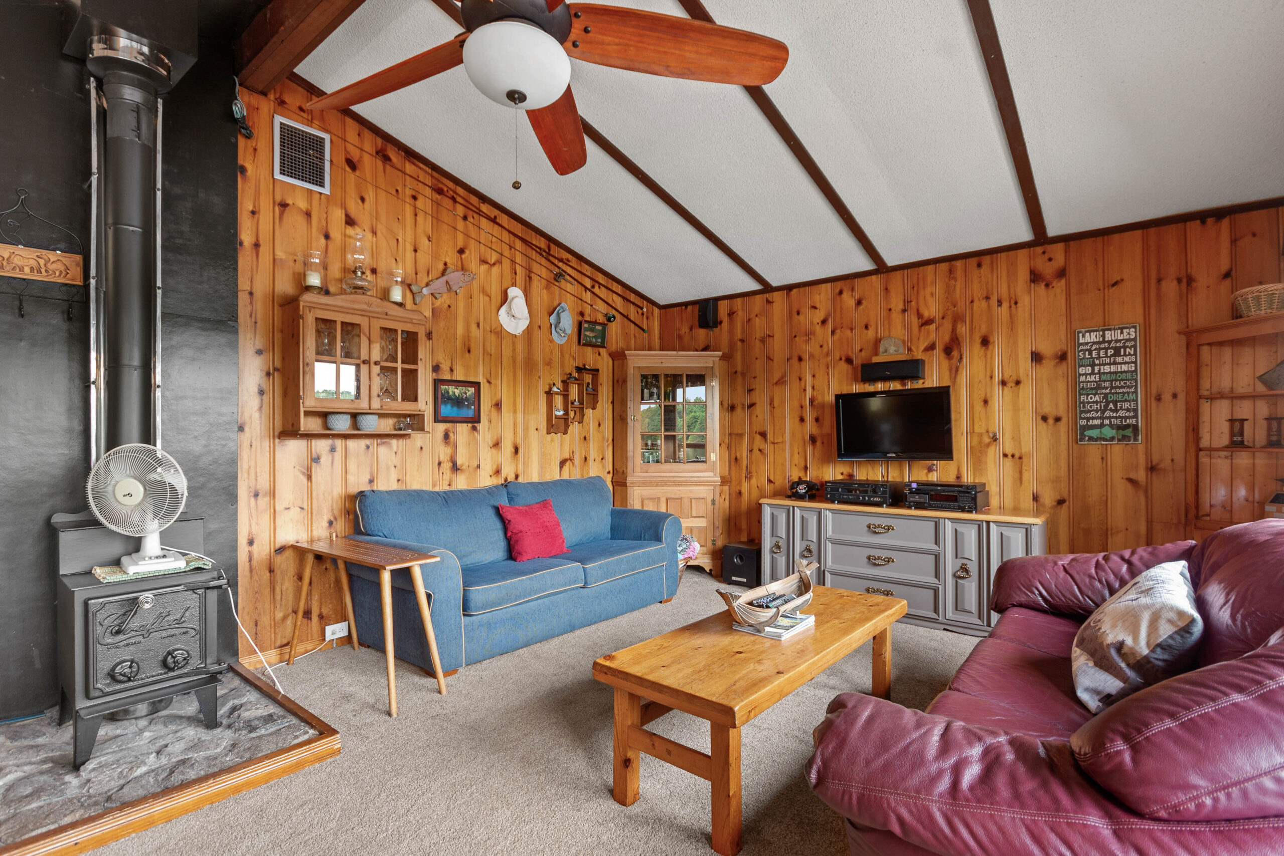 A blue couch faces a wood coffee table and burgundy leather couch in a wood room
