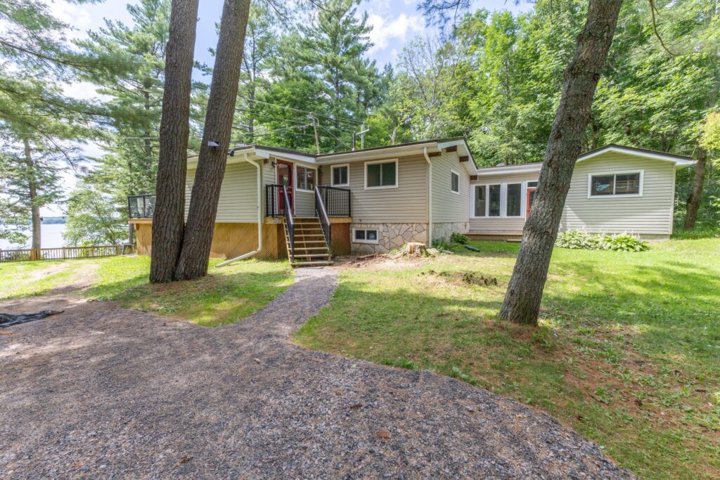 A beige paneled cottage in a forested area