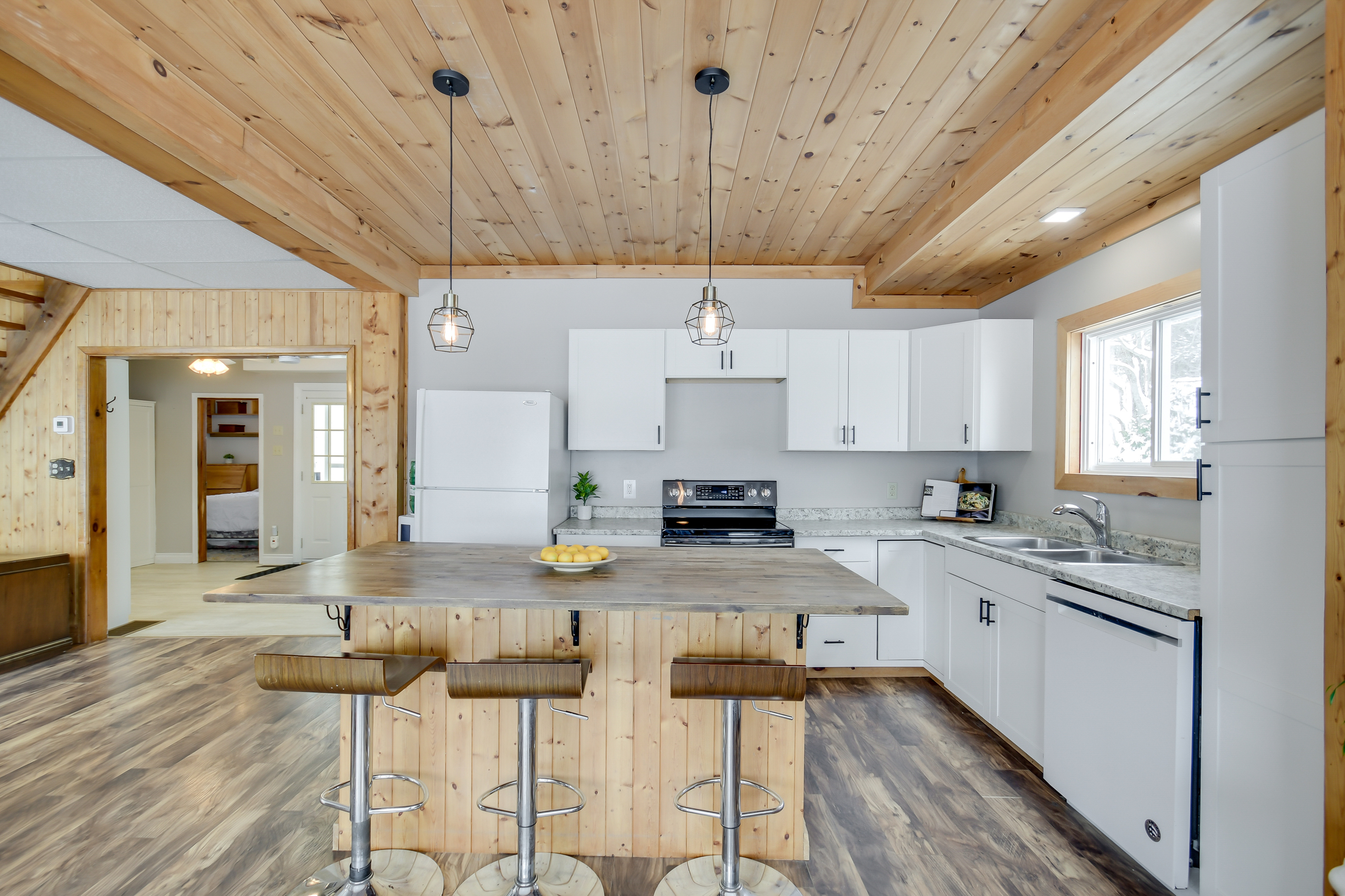 A modernized cottage kitchen with a spacious layout, white cabinets, stainless steel appliances, and a large wooden island perfect for family gatherings.