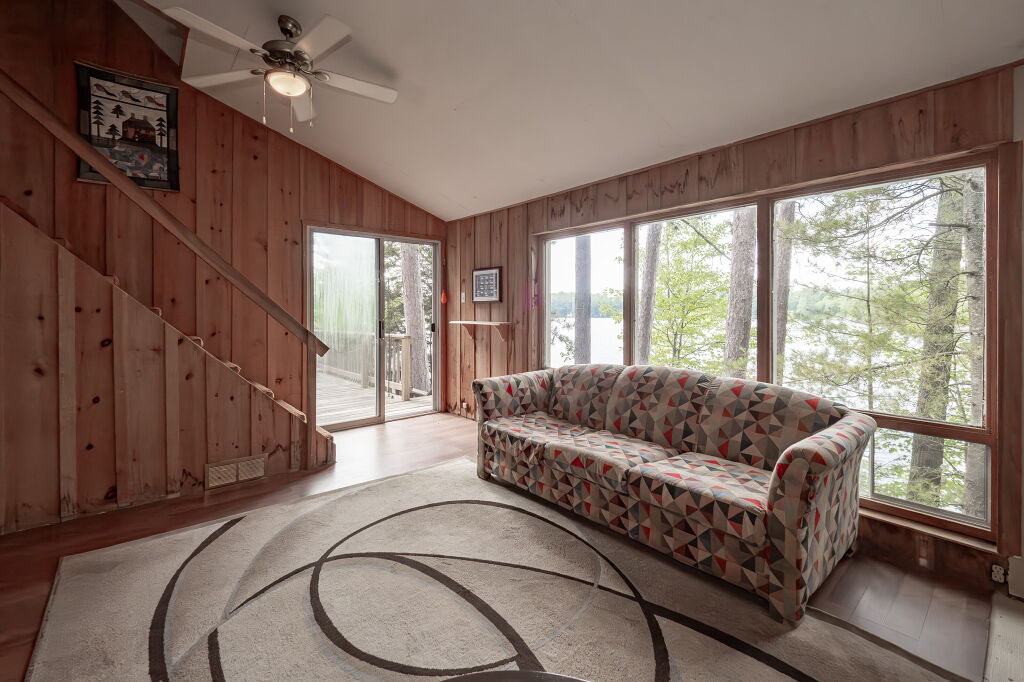 Bright sunroom with wood paneling and large windows overlooking the trees
