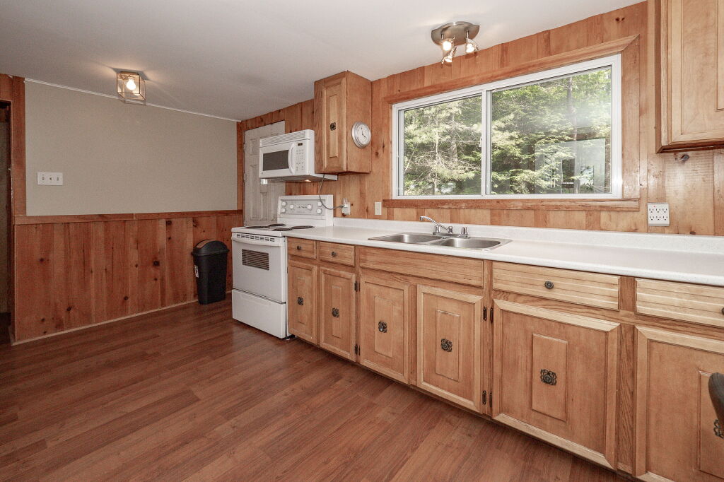 Rustic-style kitchen with wood cabinets, stove, and large window