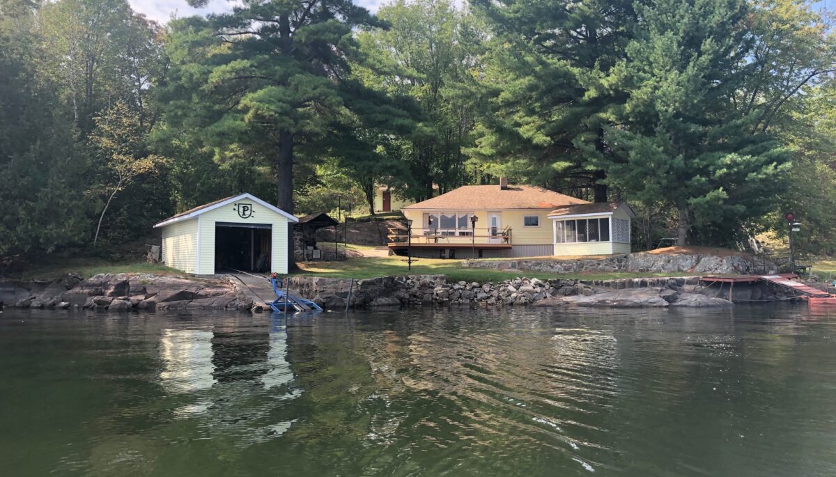 A brown bungalow cottage next to a green lake