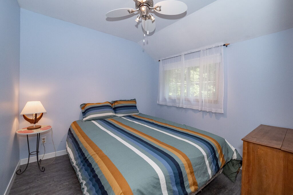 Bedroom with blue walls, striped bedspread, and ceiling fan