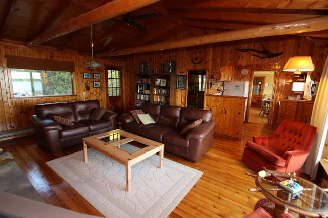 Two brown leather couches face a brown coffee table in a wood room