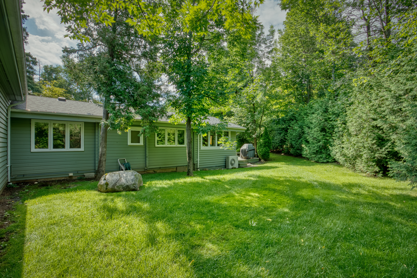 A green paneled cottage in a grassy yard