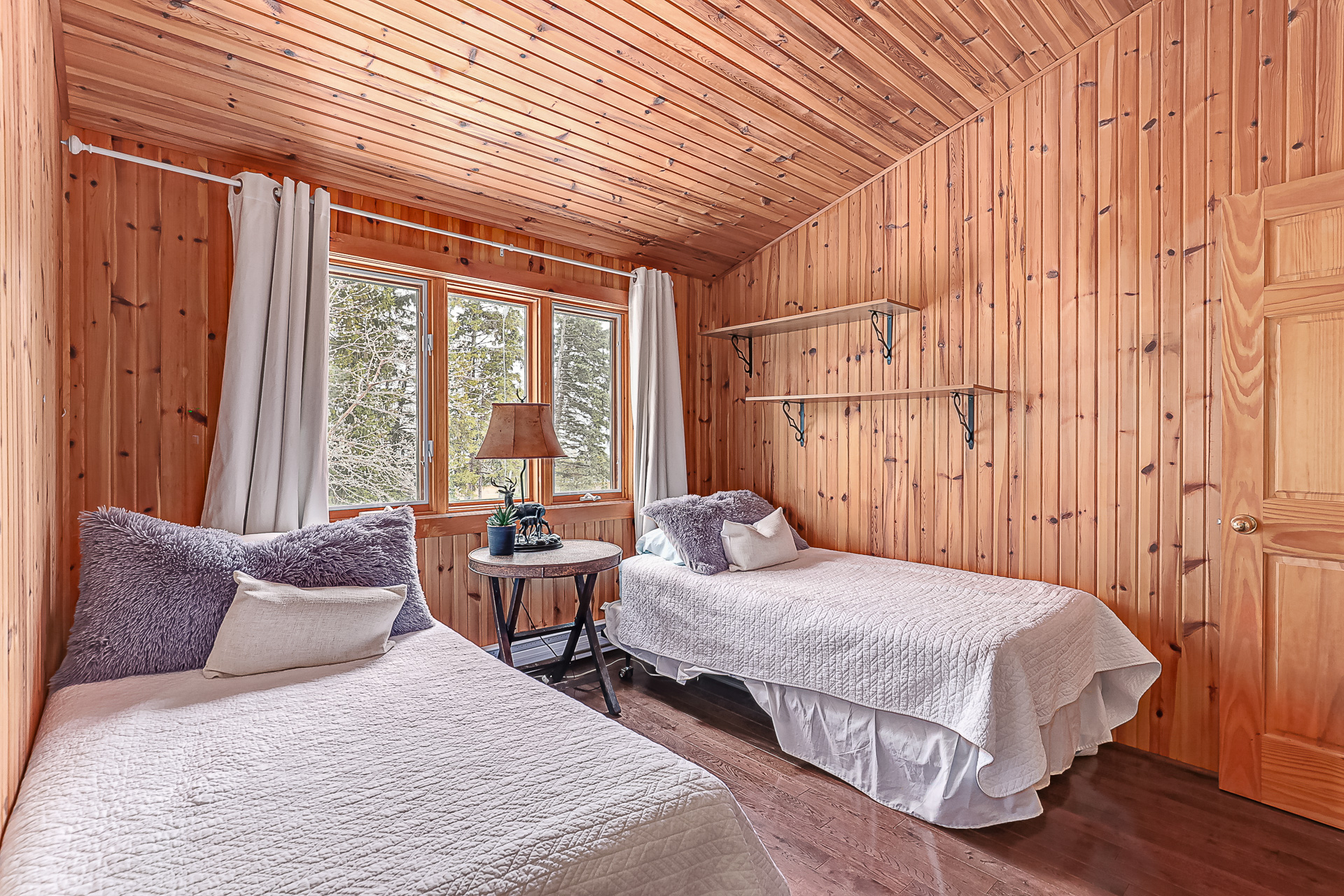 A wood-paneled room with two white beds next to each other
