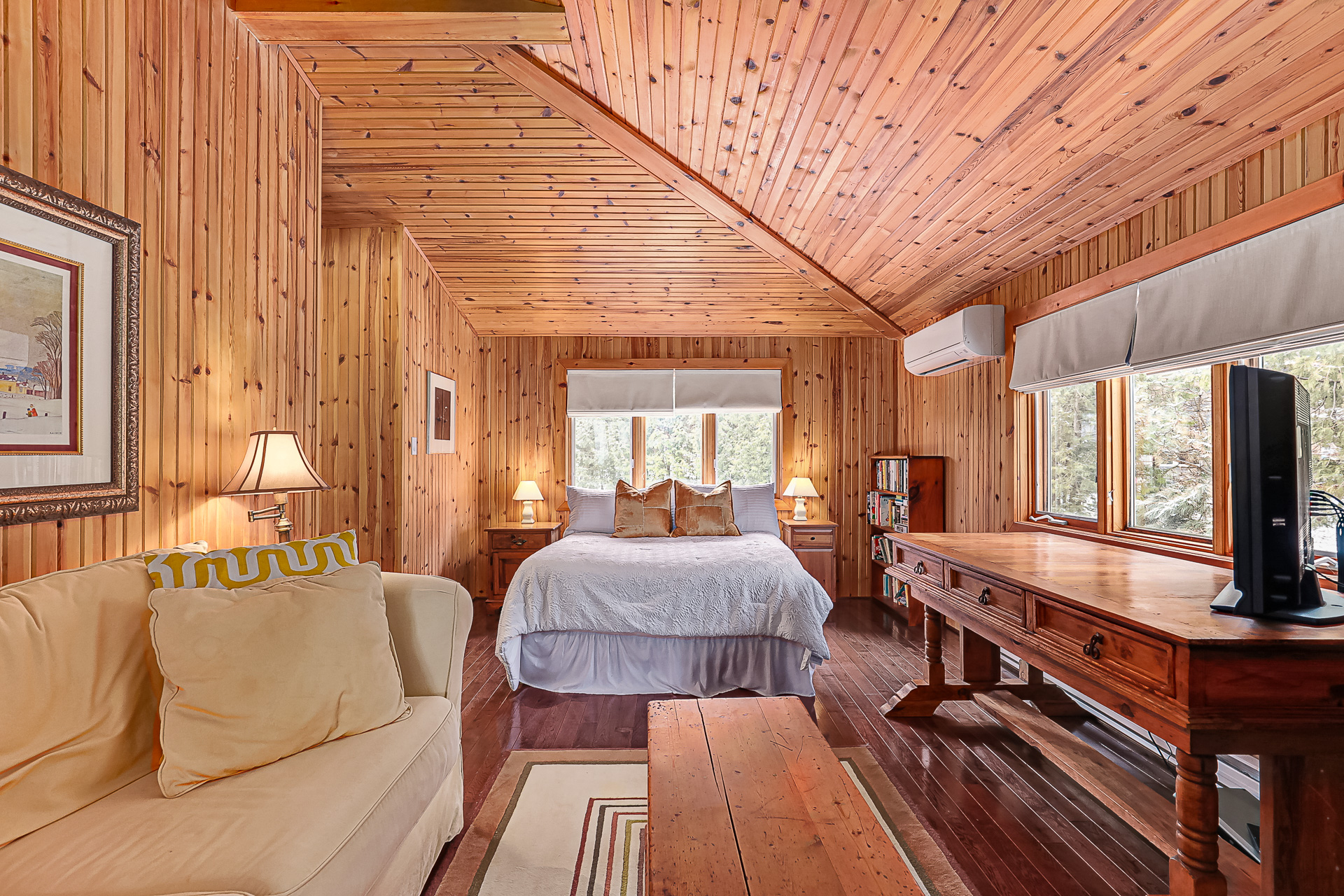 A white beg in a wood-paneled room with a slanted ceiling
