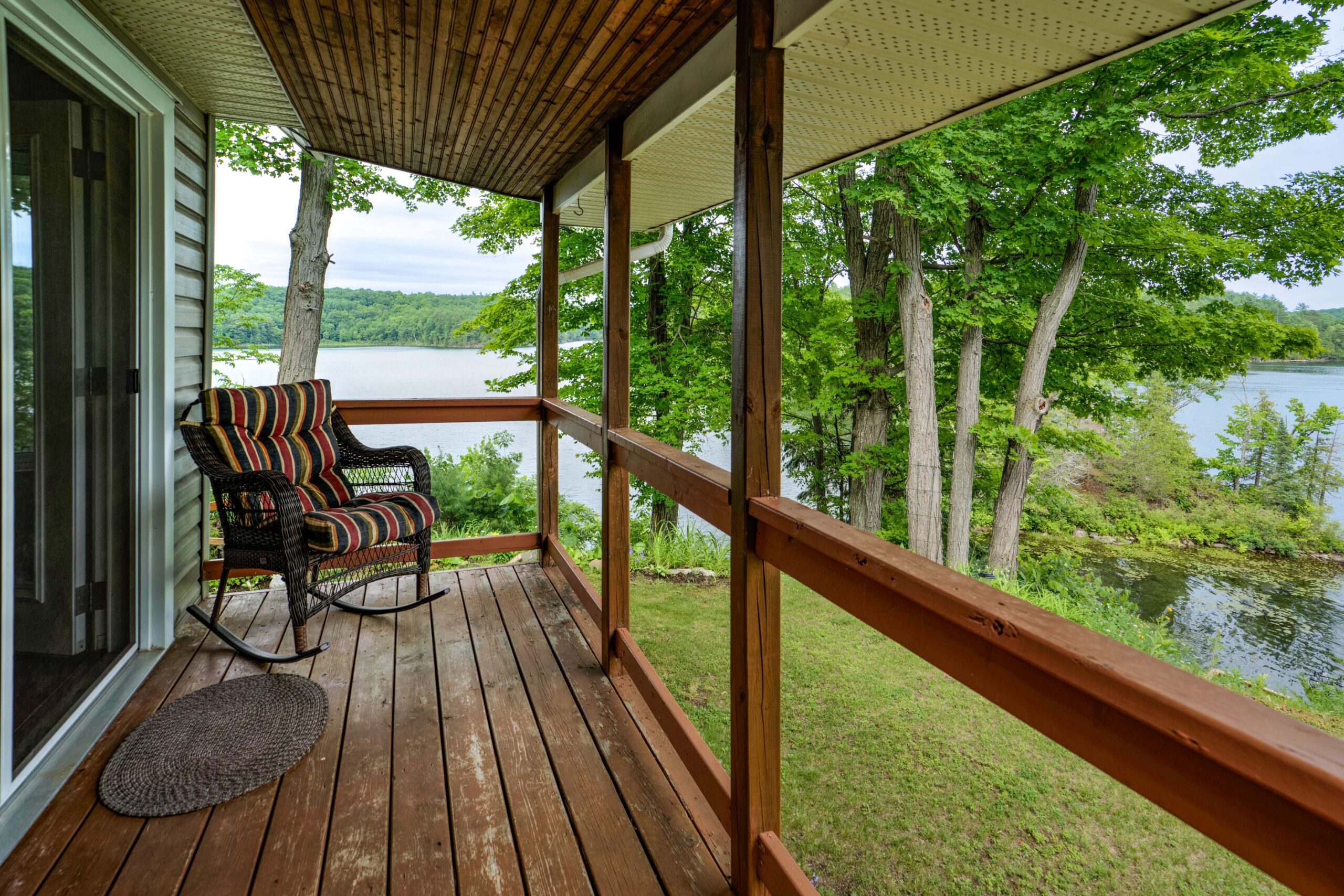 A wood deck with a small chair faces the green yard
