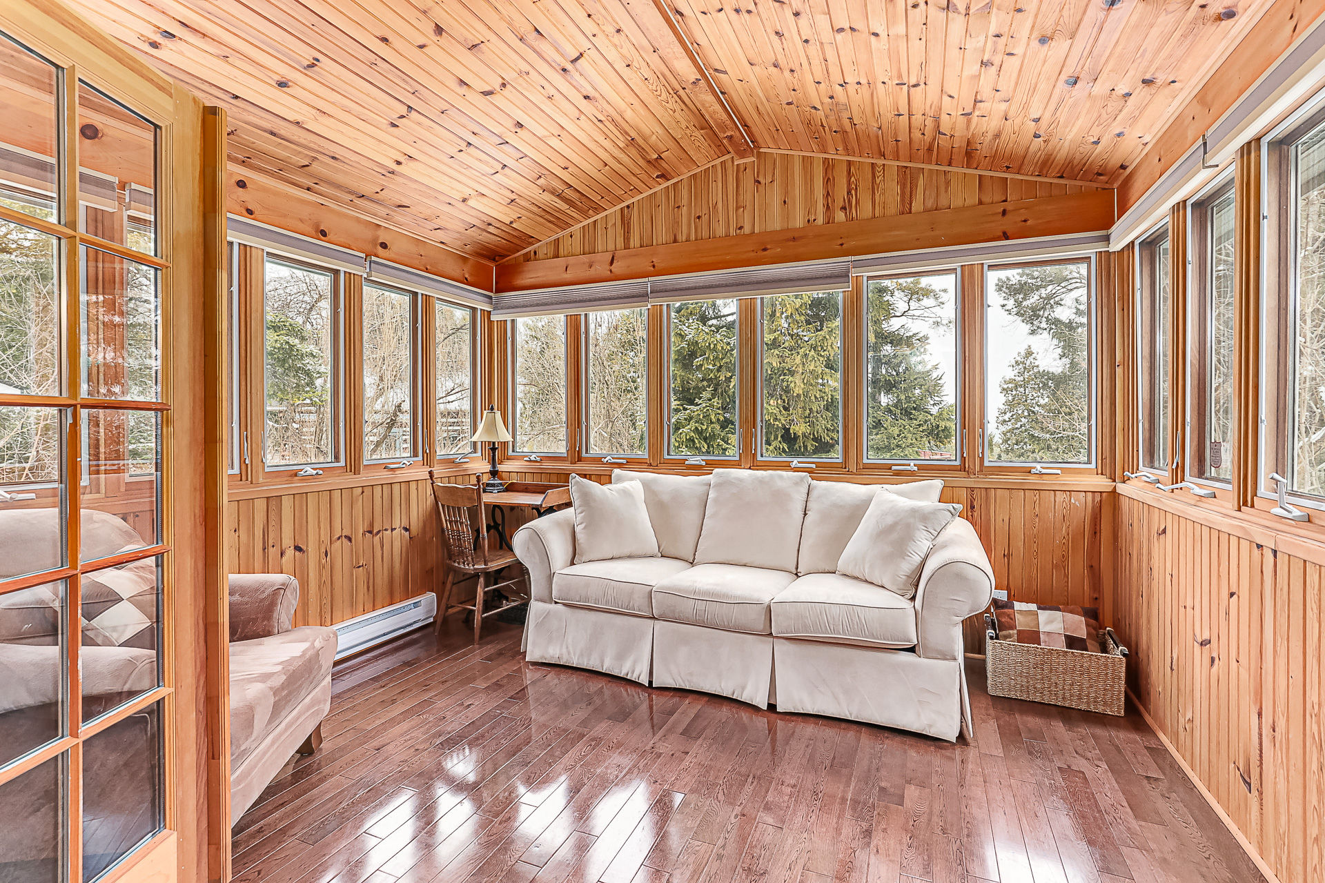 A white couch in a wood-paneled sunroom