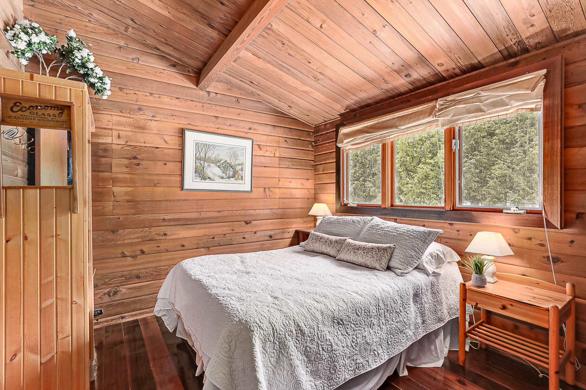 A white bed in a wood-paneled room